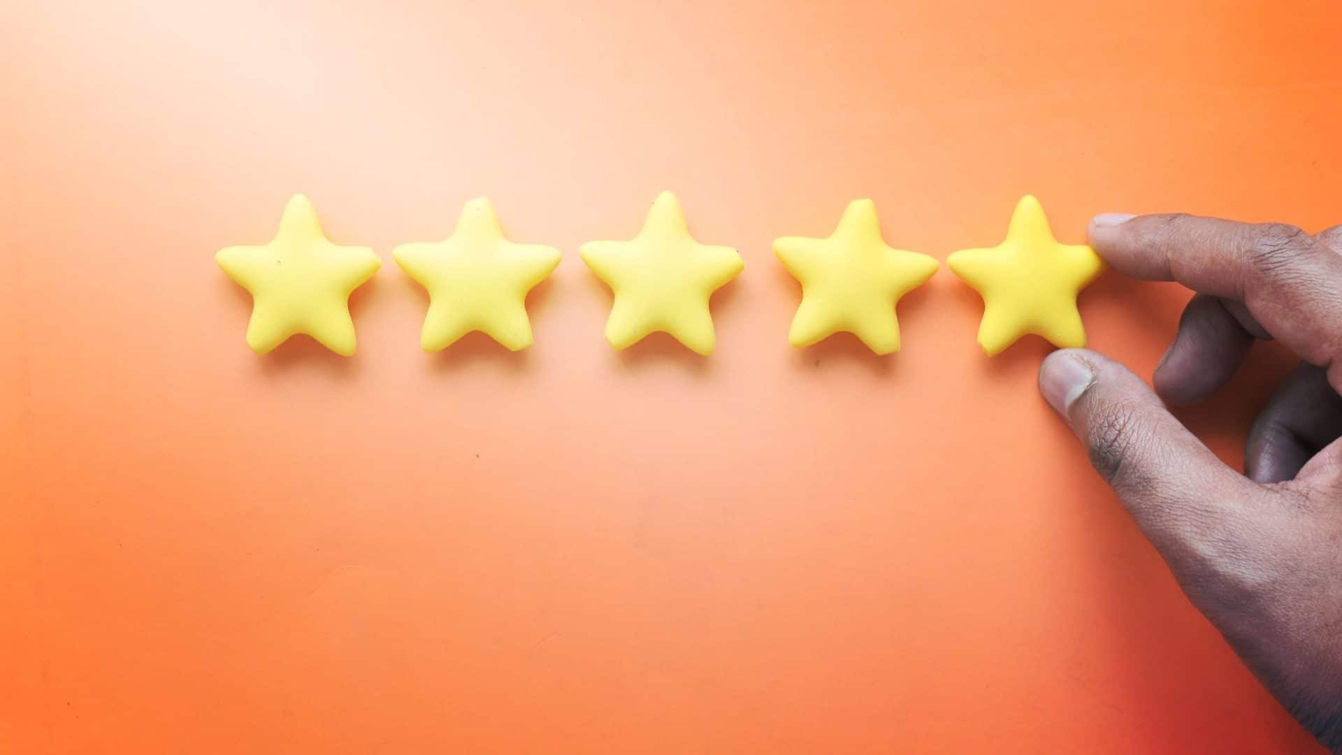 how to get more google reviews - orange background with a mans hand adding a fifth star