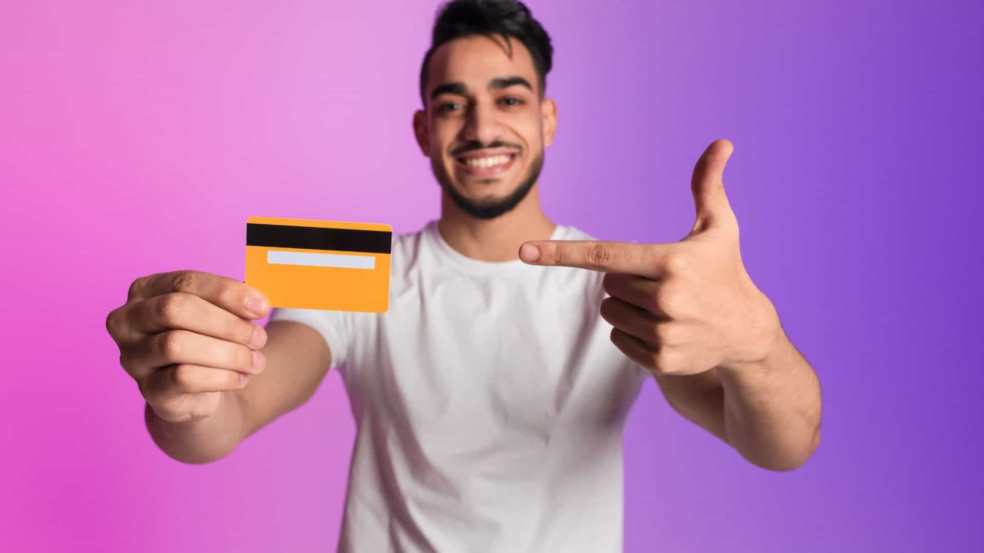 paiement échelonné pour TPE - jeune homme barbu tenant une carte bancaire et la pointant du doigt